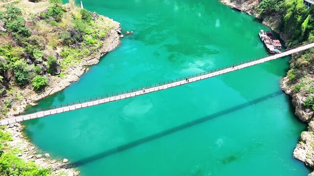 A Casual Journey: Figures Walking and Talking on a Remote Chain Bridge, Drone View