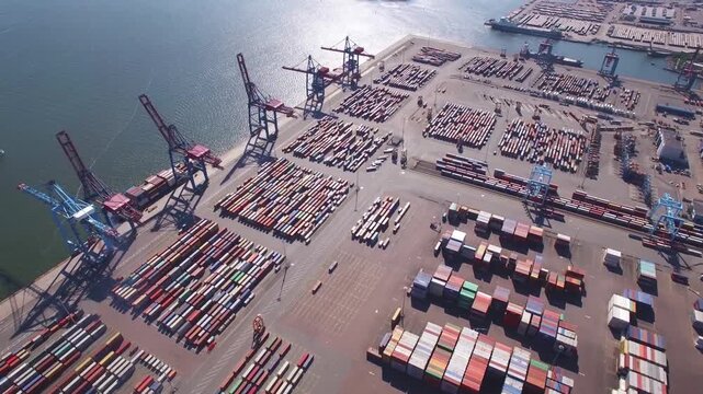A dynamic aerial time-lapse capturing the pulse of global maritime trade, with massive container ships and synchronized cranes moving under dramatic skies.