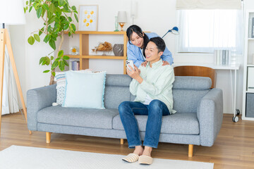 Obraz premium リビングでスマホを見るカップル