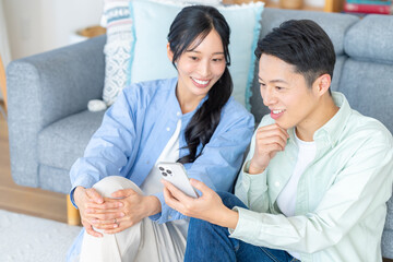 リビングでスマホを見るカップル