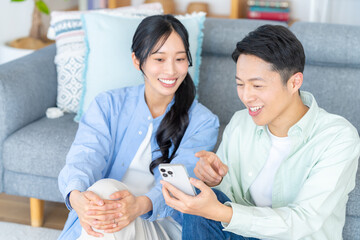 リビングでスマホを見るカップル