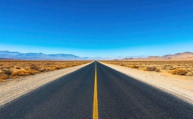 long empty desert highway stretching toward distant mountains under a clear blue sky, evoking solitude and open freedom