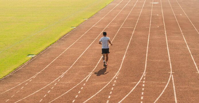 A man runs alone on a track showcasing fitness and determination in a solo practice run