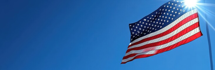 Obraz premium american flag waving against a clear blue sky with bright sun flare, evoking patriotic pride and hopeful feeling