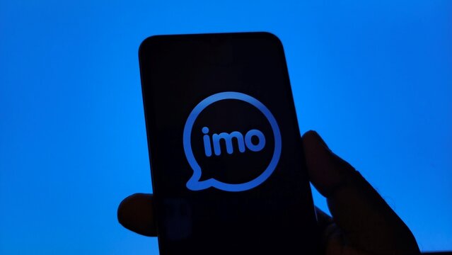 Hand holding smartphone with imo app logo on screen