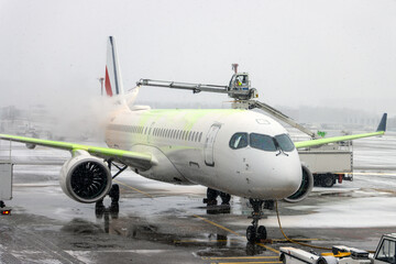 De-icing An Aircraft On The Ground With An Elevated Arm In Snow At The Airport