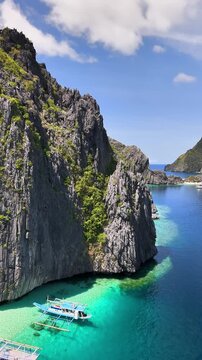 Drone hovering over Talisay Beach,some boats in the turquoise waters and blue skies in Palawan, Philippines