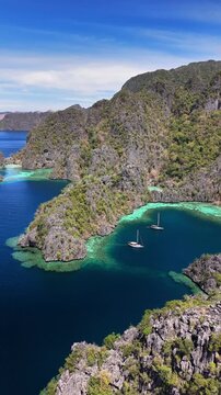 Scenic aerial view of two boats at Coron Lagoon, with blue skies and the rocky hills at Philippines