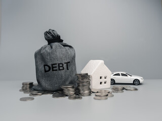 Debt concept with a dark money bag labeled "DEBT", coins stacks, white house model, and car toy symbolizing monthly expenses, loans, mortgage, insurance, and financial burden on a gray background.