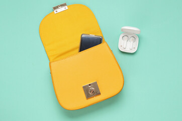 Naklejka premium Women's yellow bag with wireless earphones case on a blue background