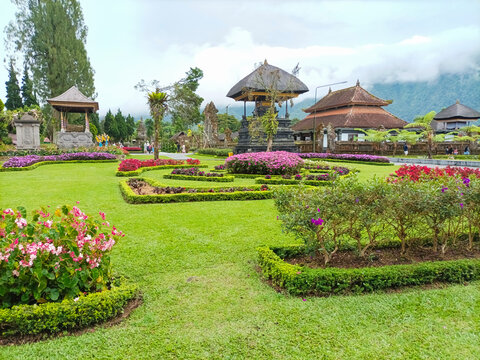 Iconic Pura Ulun Danu Beratan water temple on Lake Bratan, Bali. Lush green garden foreground. Serene Balinese landscape.