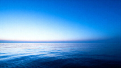 Calm ocean surface under a gradient blue sky at dawn or dusk