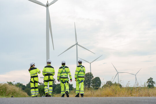 Engineer team in safety uniform walks away from wind turbine site after inspection task at wind farm supporting renewable electricity generation clean energy technology and teamwork operation