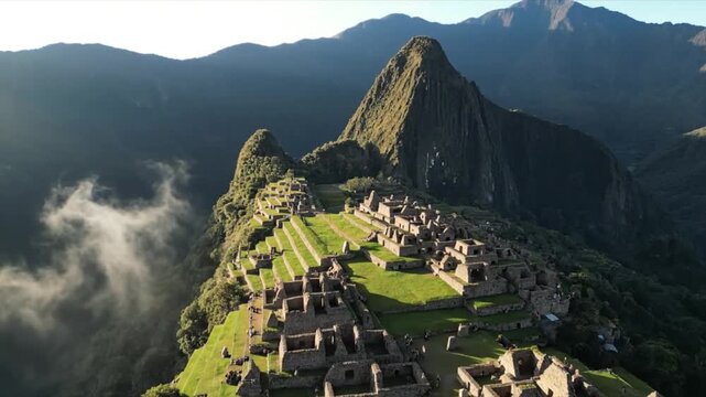 Aerial view of Machu Picchu ancient inca ruins at sunrise with fog moving through mountain valley in Peru