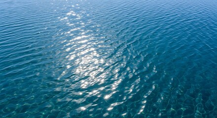 Obraz premium A serene image of the ocean under a bright sun, showcasing gentle ripples and shimmering light on the water's surface. 