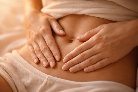 Woman stomach pain abdomen myoma uterine fibroids endometrial polyp health Woman holds lower stomach soft light suggesting abdominal pain from myoma uterine fibroids endometrial polyp and intimate