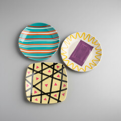 Three Colorful Decorative Plates with Geometric Patterns and Stripes on Gray Background