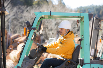 フォークリフトで木材を運ぶ作業員全身(多摩木材センター協同組合プロパティ許可ずみ）