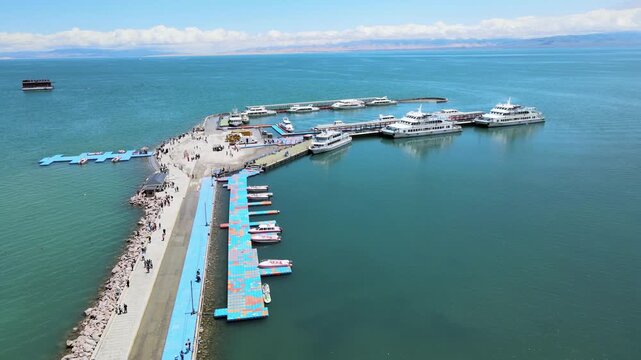A dynamic aerial time-lapse capturing the rhythmic pulse of global trade at a bustling port, with massive container ships and synchronized cranes under dramatic skies.