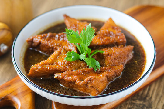 Close-up bowl of Braised Tofu (Tahu Semur). These tender tofu triangles are slow-braised in a fragrant, sweet soy sauce gravy, creating a perfect balance of savory and sweet.