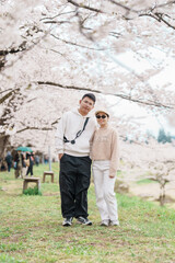 Couple tourist sightseeing Sakura Cherry Blossom in Spring. Happy traveler travel near Hinokinai River riverbank in Kakunodate town, Semboku District, Akita Prefecture, Japan. Landmark and Vacation
