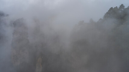 A mystical misty landscape. High rock pillars are shrouded in fog. Peaks in the clouds. Steep...