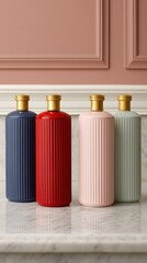 Four stylish, ribbed bottles in varying colors-navy, red, pink, and green-are displayed on a marble surface against a soft pink backdrop.