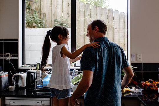 Father teaching daughter how to wash dishes in the kitchen