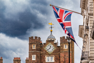 Union Jack over historic clock tower at St James’s Palace, London, UK British flag with Tudor-style clock tower architecture under dramatic sky, London © Iliya Mitsk