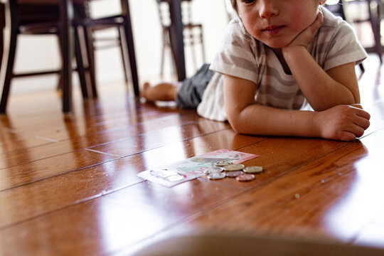 Young boy lying on the floor counting money