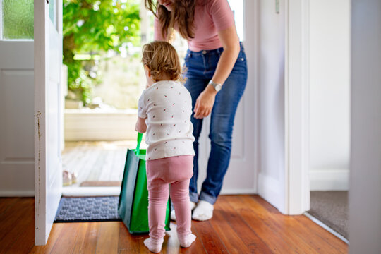 Toddler girl helping mum carry green shopping bag
