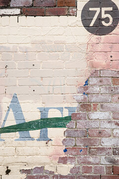 Distressed brick wall with faded lettering and a prominent number 75 in a circle