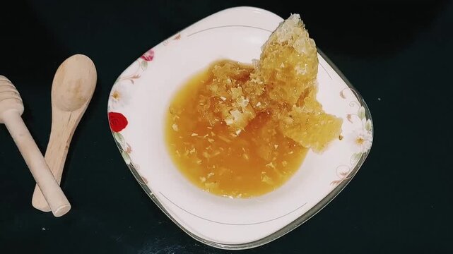 Close up view of raw honeycomb and golden honey bowl