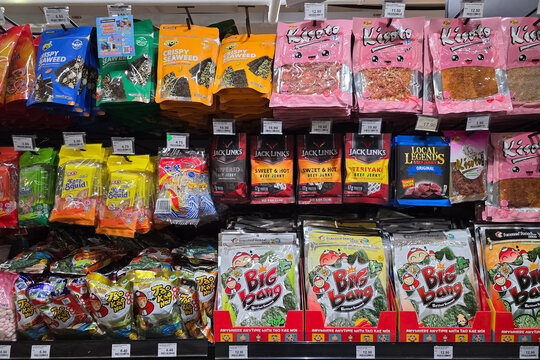 Penang, Malaysia &ndash; November 6, 2025: Variety of packaged seaweed snacks, dried squid and beef jerky brands including Tao Kae Noi and Jack Link&rsquo;s displayed on supermarket shelves.