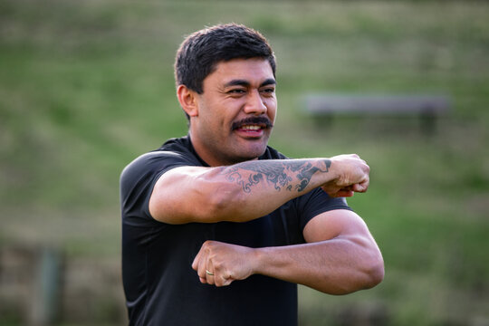 Samoan man posing haka dance move in a green field