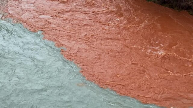 Two rivers with different colors flowing together without mixing. Natural phenomenon of confluence of rivers. Water texture close up. Slow motion.