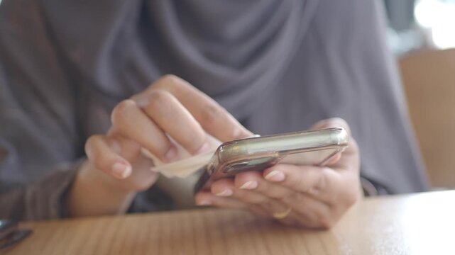 Cleaning a smartphone at a cafe table in the afternoon