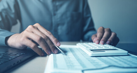 Financial analysis and accounting concept with calculator, pen, laptop, and financial documents. Represents audit process, bookkeeping, budget calculation, business finance management.