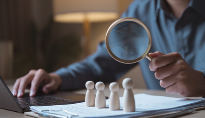 Human resources recruitment concept with magnifying glass and candidate figures on documents....