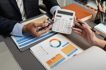 A business meeting scene where professionals review financial charts and exchange insights, highlighting strategic planning and collaborative decision making in a modern office environment.
