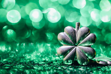 Silver shamrock clover on a sparkling green background with festive bokeh lights. St. Patrics Day...