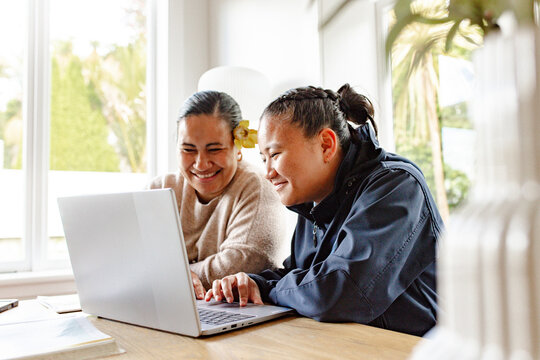 Samoan mum helping teenage daughter with homework using laptop