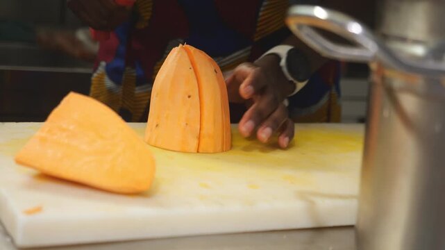 Slow motion close up shows a woman chef slicing yam sweet potato (Ipomoea batatas), also known as igname, &ntilde;ame, inhame, batata, kumara, camote and boniato