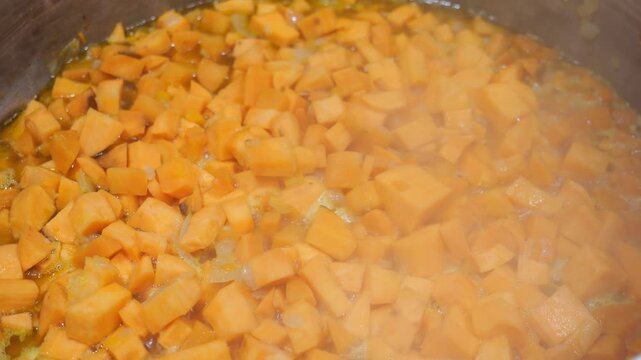 Yam cubes saut&eacute;ing in a pot for traditional veloute soup recipe preparation close up