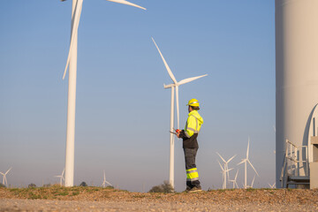 Engineer man working with tablet at windmill farm Generating electricity clean energy. Wind turbine...