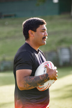 Man with a beard holding ruby ball in a sports field
