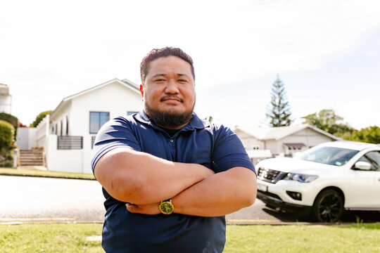 Samoan man standing with arms crossed outdoors in the driveway
