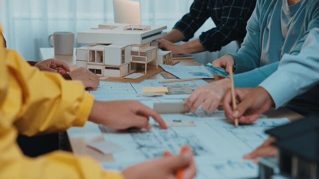 A group of architects engages in a collaborative session, reviewing models and sketches on the table, enhancing their creative process and project development in a bright office. SACTR