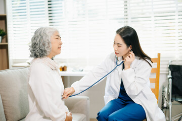 Obraz premium Healthcare professional using stethoscope to examine elderly woman at home. Senior medical checkup, heart health, home care, diagnosis, prevention