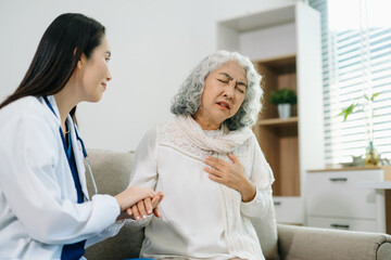 Obraz premium Female doctor supporting elderly woman at home during medical visit. Senior healthcare, home care, patient support, wellness, trust and professional medical assistance concept.